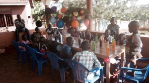 A photo of some of the children at Barb's Home of Angels getting ready for their Christmas dinner! In the middle of the table is a tree they found, which they placed in a pot, and decorated with balloons